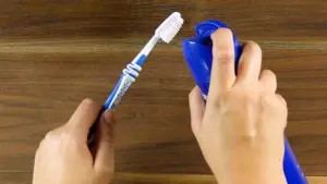 Bàn tay cầm bàn chải đánh răng để chà vết sơn móng tay đã xịt keo