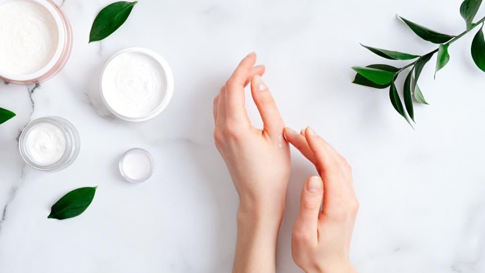 Bàn tay người mẹ bầu đang thoa kem dưỡng ẩm, chăm sóc móng tay và da tay khỏe mạnh trong 3 tháng đầu.