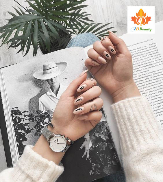 Bàn tay với bộ móng tay đính đá lấp lánh, tạo dáng chạm môi, toát lên vẻ quyến rũ và sang trọng