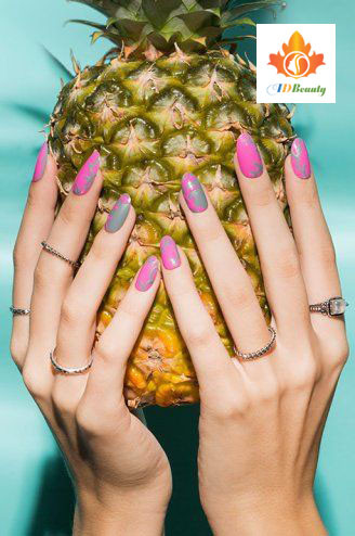 Bàn tay với bộ nail màu cam đất, đặt trên một chiếc đĩa gỗ chứa những viên đá cuội và lá khô, mang phong cách mộc mạc