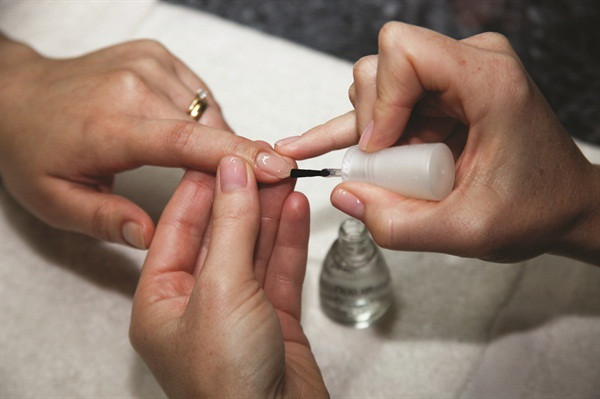 Bàn tay với móng được phủ sơn lót, minh họa lợi ích bảo vệ móng khỏi ố vàng