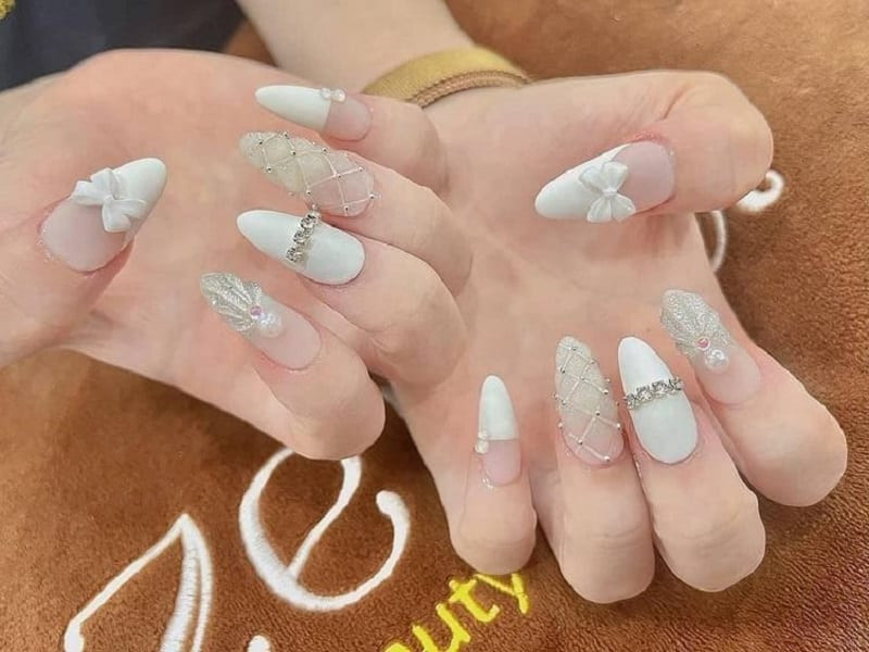 Bộ nail tay được kết hợp hài hòa giữa các charm đính đá, ngọc trai và nơ trắng