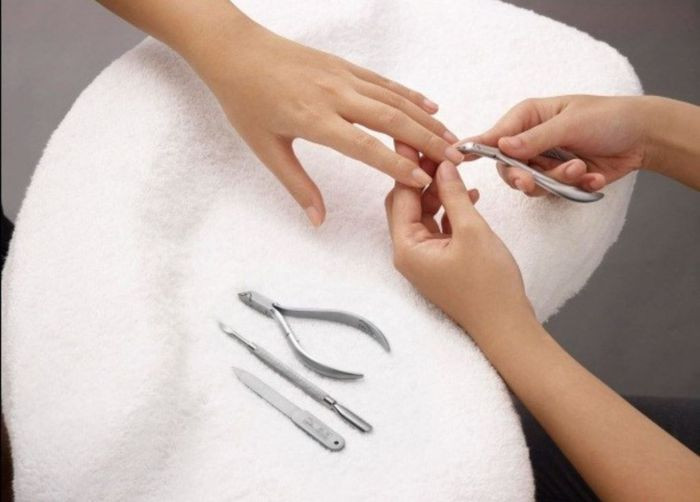 Hình ảnh bàn tay đang sử dụng kềm để cắt móng tay, nhấn mạnh việc vệ sinh dụng cụ khi nên cắt móng tay ngày nào.