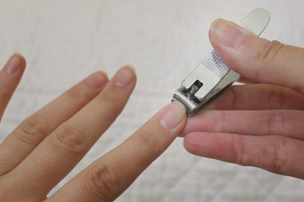 Hình ảnh bàn tay và dụng cụ cắt móng trong điều kiện ánh sáng yếu thời xưa