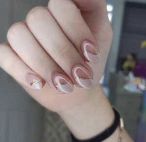 Mẫu nail trong suốt pha chút sắc hồng, nhấn nhá một phần nail bằng sơn trắng và nhũ vàng
