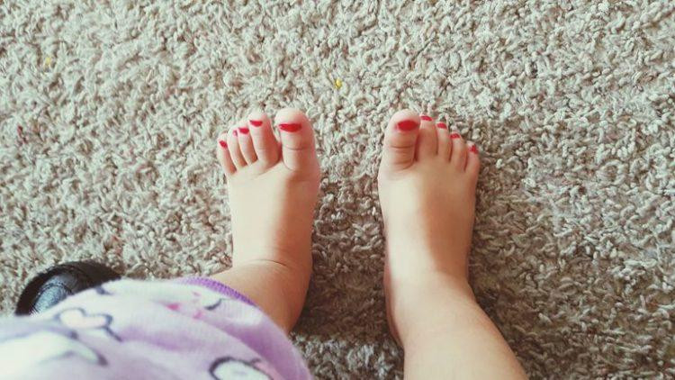 Mẹ đang tỉ mỉ sơn móng chân cho bé gái, minh họa cách làm móng tay cho trẻ em một cách an toàn và nhẹ nhàng tại nhà.