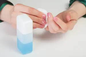 Miếng bông tẩm acetone chuẩn bị loại bỏ vết sơn móng tay trên quần áo