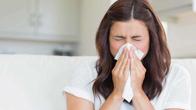 Mô tả một người phụ nữ đang ngâm các ngón tay vào một bát thủy tinh chứa dung dịch tẩy móng, bên cạnh là một lọ nước tẩy sơn móng tay.