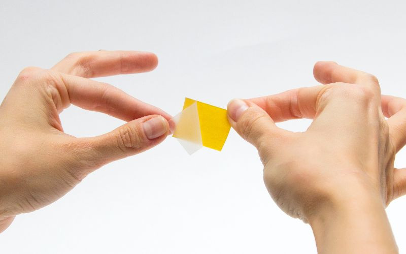 Mô tả việc sử dụng băng keo hai mặt để dán móng giả, phương pháp an toàn nhưng có độ bền hạn chế so với việc dán móng tay bằng keo 502.