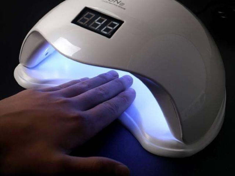 Móng tay được hơ khô dưới ánh đèn của máy làm khô móng tay UV LED
