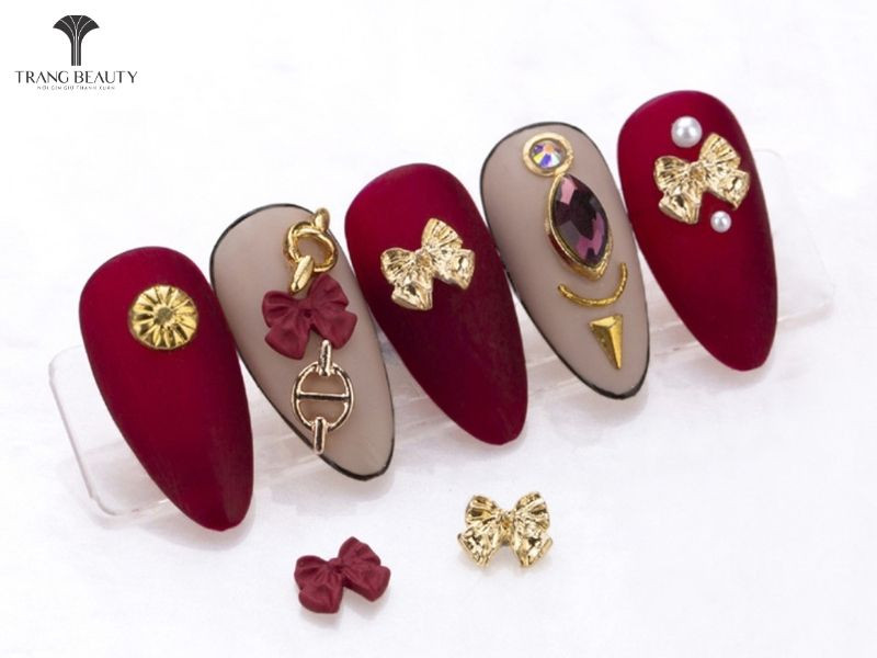 Móng tay hình nơ đỏ đính nhiều phụ kiện charm nổi bật