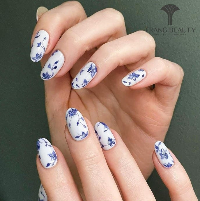Móng tay màu gạo với cành hoa mềm mại được vẽ tinh tế trên nền trắng