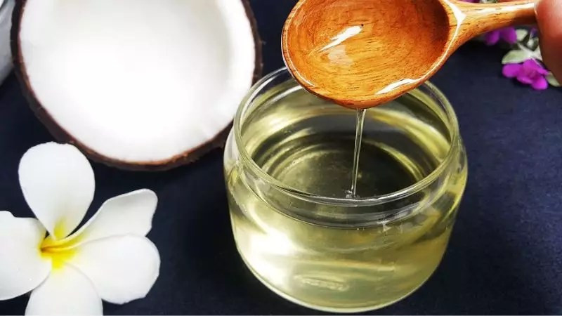 Một bàn tay đang được ngâm trong bát nước có dầu dừa để chăm sóc móng sau khi sơn bóng