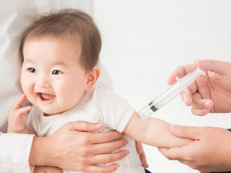 Một bé gái đang được tiêm vắc-xin vào cánh tay, thể hiện tầm quan trọng của việc tiêm phòng uốn ván sau khi bị dằm đâm vào móng tay hoặc da