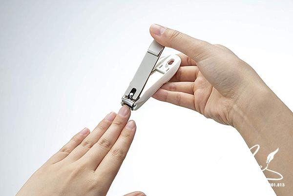 Một người phụ nữ đang cắt tỉa móng tay của mình, tượng trưng cho việc chăm sóc móng vào ngày tốt cắt móng tay 2024