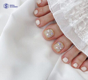Nail chân màu trắng kết hợp sơn nhũ ở ngón cái, tạo hiệu ứng lấp lánh và thu hút ánh nhìn