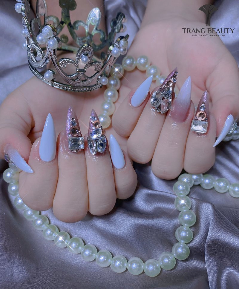 Nail Hàn Quốc đính đá pha lê trên nền hồng phấn, kết hợp chi tiết kim loại nhỏ tạo điểm nhấn ấn tượng.