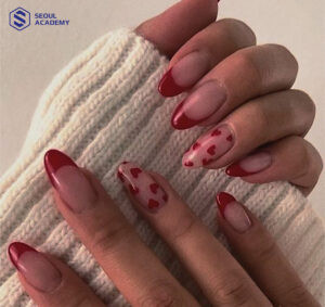 Nail màu đỏ mận kết hợp màu sơn trắng với hoạ tiết trái tim ngọt ngào, trẻ trung