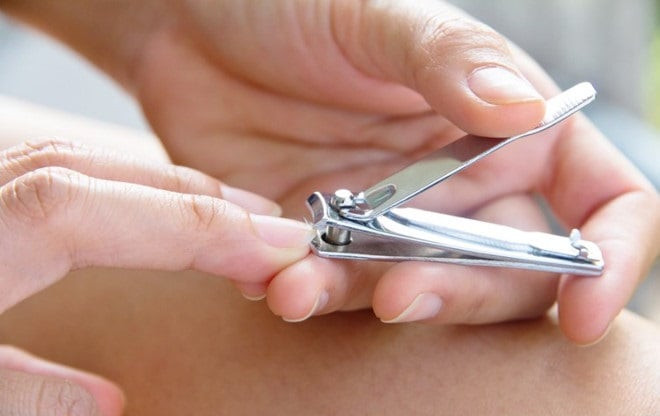 Người phụ nữ đang cắt móng tay cẩn thận, minh họa việc chăm sóc móng tay