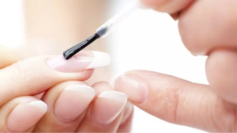 Người phụ nữ đang sơn lớp sơn bóng móng tay lên bộ nail màu pastel