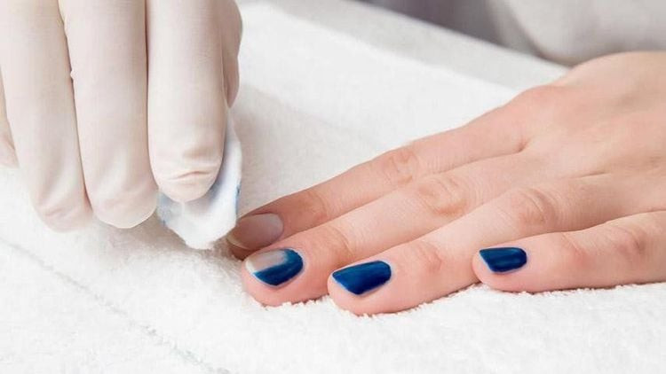 Người phụ nữ đang tẩy sơn móng tay bằng bông thấm dung dịch, minh họa việc **cồn có tẩy được sơn móng tay không** và các giải pháp khác