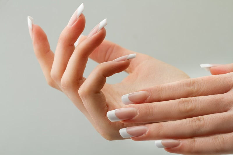 Phụ nữ với bàn tay thon dài và móng tay nhanh dài được chăm sóc kỹ lưỡng